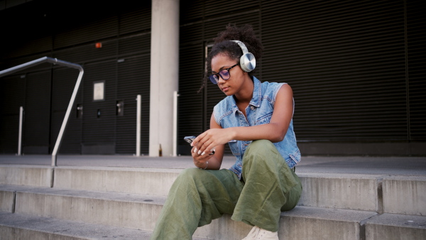 A video of gorgeous young woman with eyeglasses in the city, headphones on head.