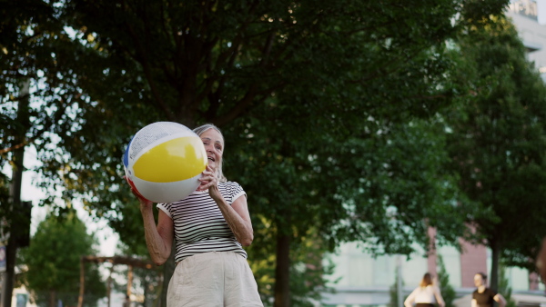 Elderly couple in love spending hot evening the city park, playing with ball. Staycation concept.