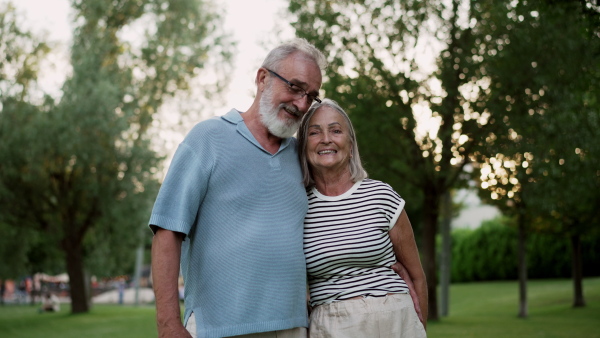 Elderly couple in love hanging out in public park, enjoying beautiful summer evening. Staycation concept.