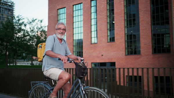 A senior man enjoying hot summer in the city, going on bike ride around the city. Staycation concept.