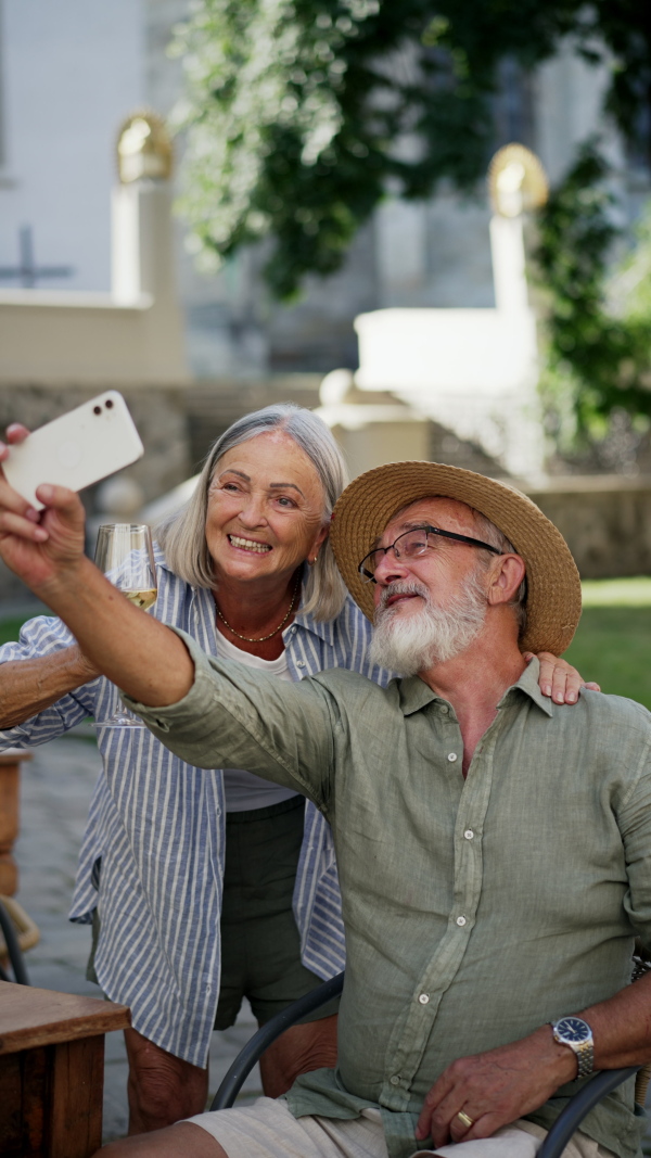 A senior couple taking selfie. Pensioners enjoying hot summer in the city, sightseeing, taking walk in historic part of city. Staycation concept.