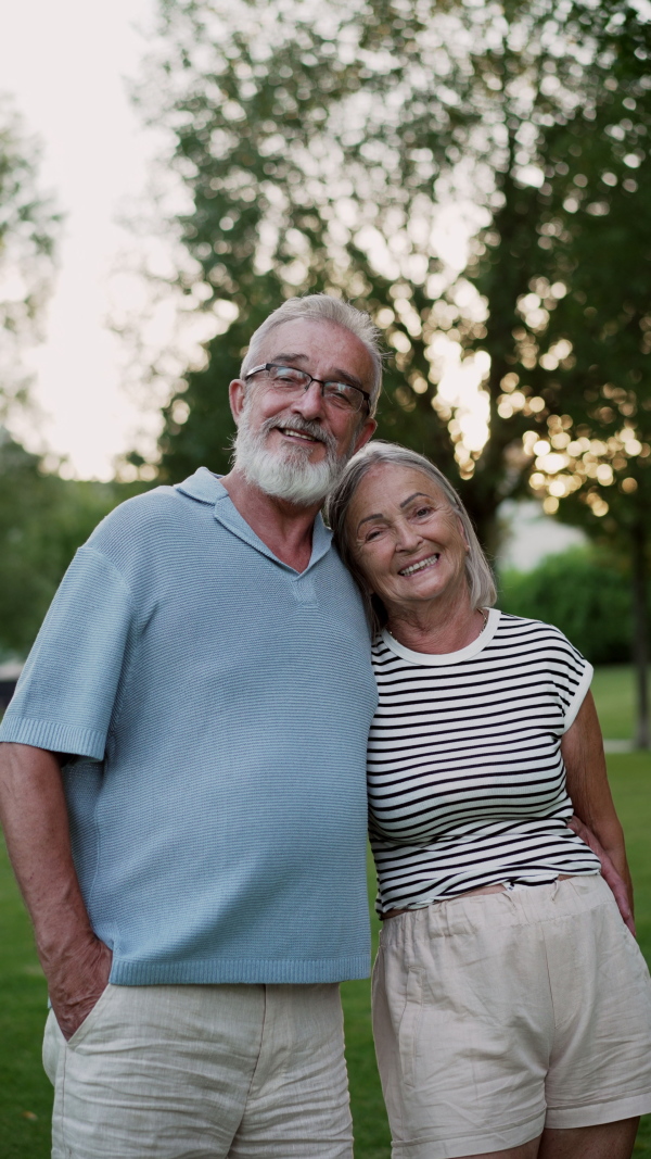 Elderly couple in love hanging out in public park, enjoying beautiful summer evening. Staycation concept.