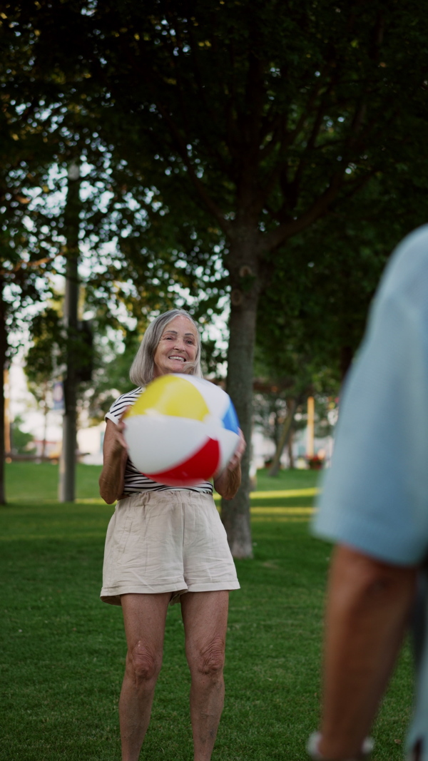 Elderly couple in love spending hot evening the city park, playing with ball. Staycation concept.