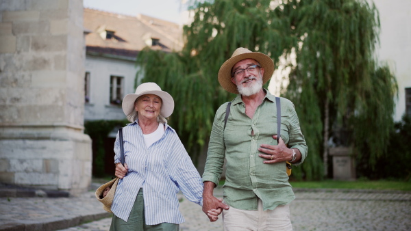 A senior couple enjoying hot summer in the city, sightseeing, taking walk in historic part of city. Staycation concept.