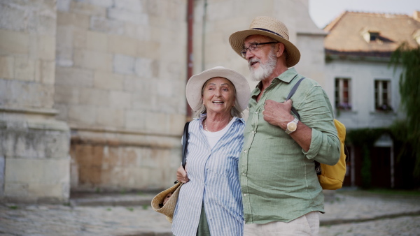 A senior couple enjoying hot summer in the city, sightseeing, taking walk in historic part of city. Staycation concept.