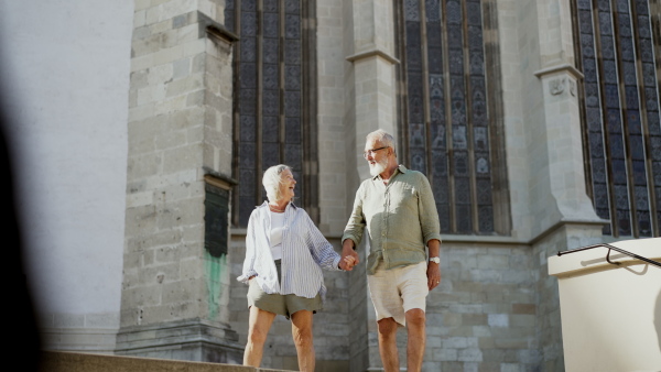 A senior couple enjoying hot summer in the city, sightseeing, taking walk in historic part of city. Staycation concept.