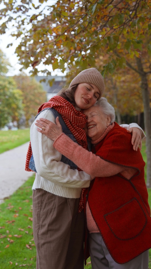 A video of granddaughter on an autumn walk in the park with her grandmother, hugging.