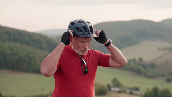 An elderly man on bike ride in autumn nature, getting ready for the ride. Active older man on electric bicycle.