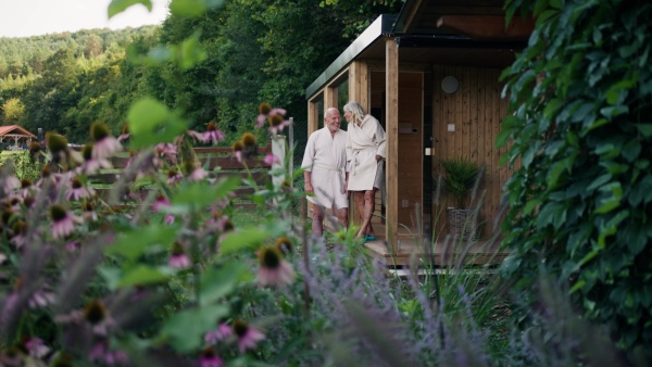 Older couple in love wearing bathrobe, getting ready to go into home sauna. Concept of hygge and slow life for senior people.