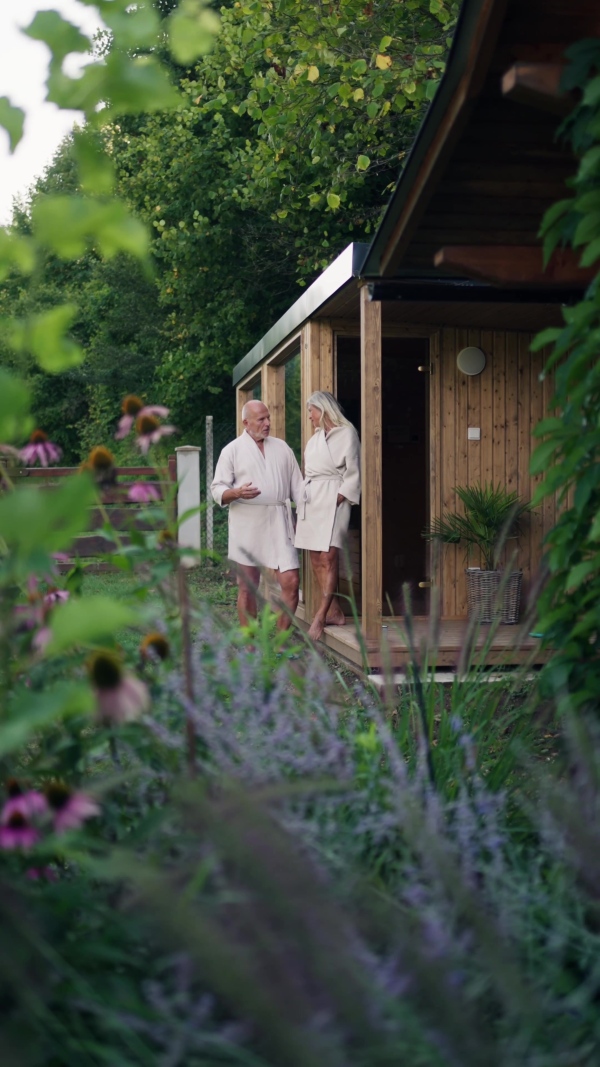 Older couple in love wearing bathrobe, getting ready to go into home sauna. Concept of hygge and slow life for senior people.