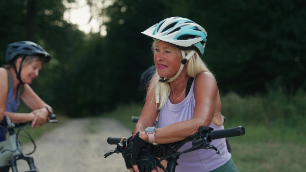 A video of beautiful senior cyclist on bike tour in nature with friends. Older woman on low impact route riding electric bikes.