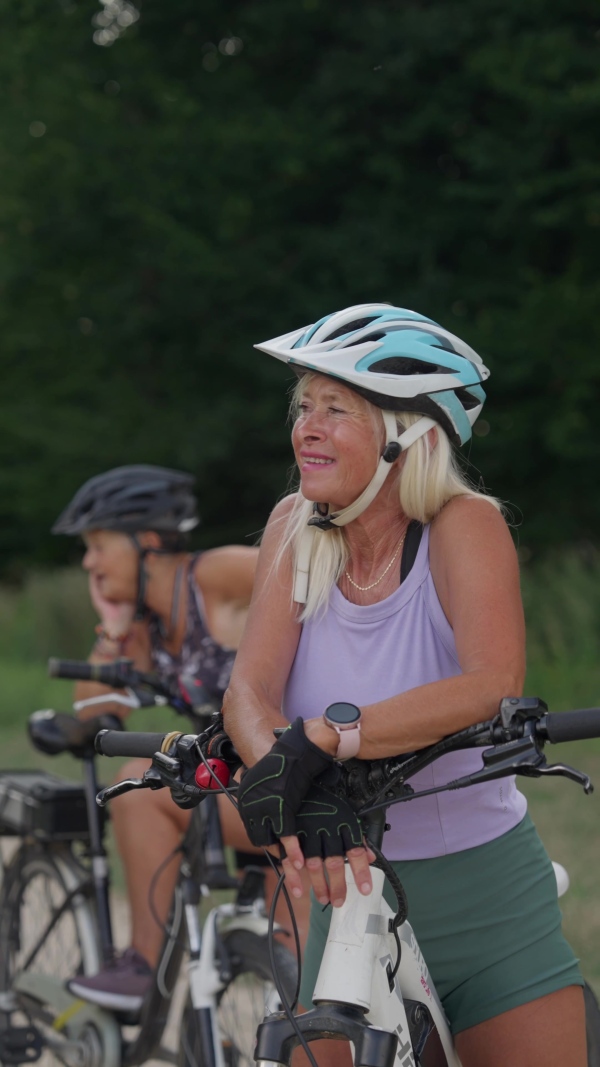 A video of beautiful senior cyclist on bike tour in nature with friends. Older woman on low impact route riding electric bikes.