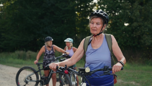 A video of beautiful senior cyclist on bike tour in nature with friends. Older woman on low impact route riding electric bikes.