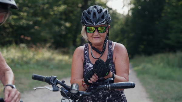 A video of beautiful senior cyclist on bike tour in nature. Older woman on low impact route riding electric bikes.