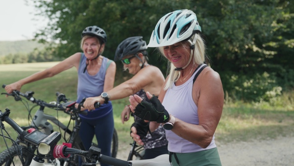 A video of beautiful senior cyclist on bike tour in nature with friends. Older woman on low impact route riding electric bikes.