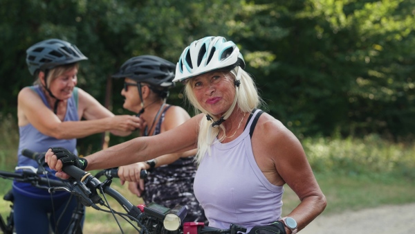 A video of beautiful senior cyclist on bike tour in nature with friends. Older woman on low impact route riding electric bikes.