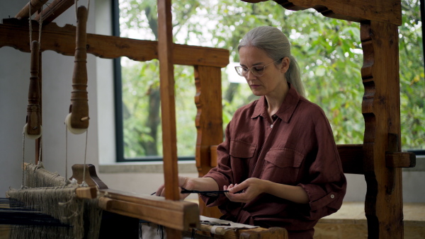 Woman in a weaving course is learning to weave on a loom. New Year's resolutions, developing personal creativity.