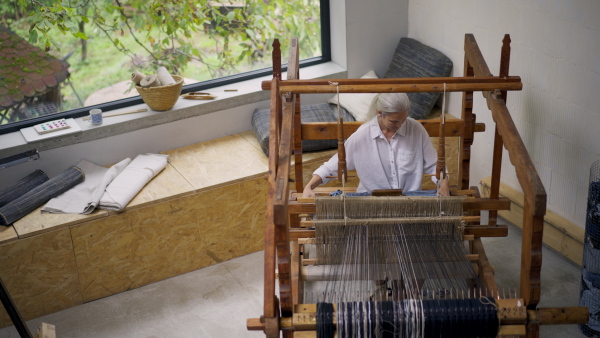 Woman in a weaving course is learning to weave on a loom. New Year's resolutions, developing personal creativity.