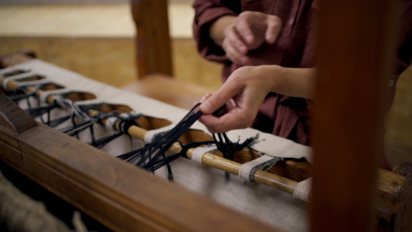 Close up of a woman in a weaving course is learning to weave on a loom. New Year's resolutions, developing personal creativity.