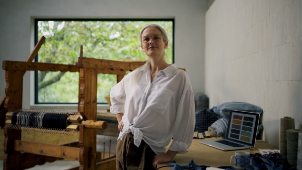 A happy businesswoman in weaving workshop. Sustainable business, using recycled materials in fashion.