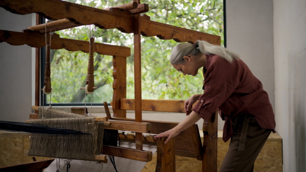 Woman in a weaving course is learning to weave on a loom. New Year's resolutions, developing personal creativity.