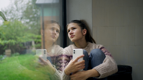 A teenage girl crying after reading cruel text. Teen depression.