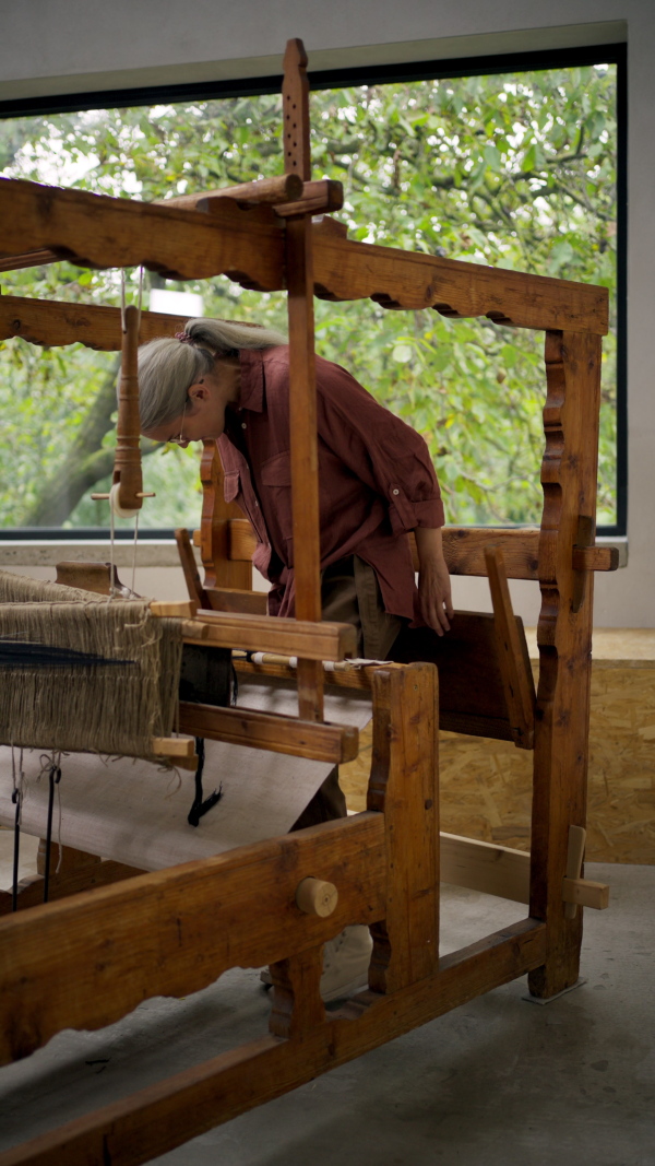 Woman in a weaving course is learning to weave on a loom. New Year's resolutions, developing personal creativity.