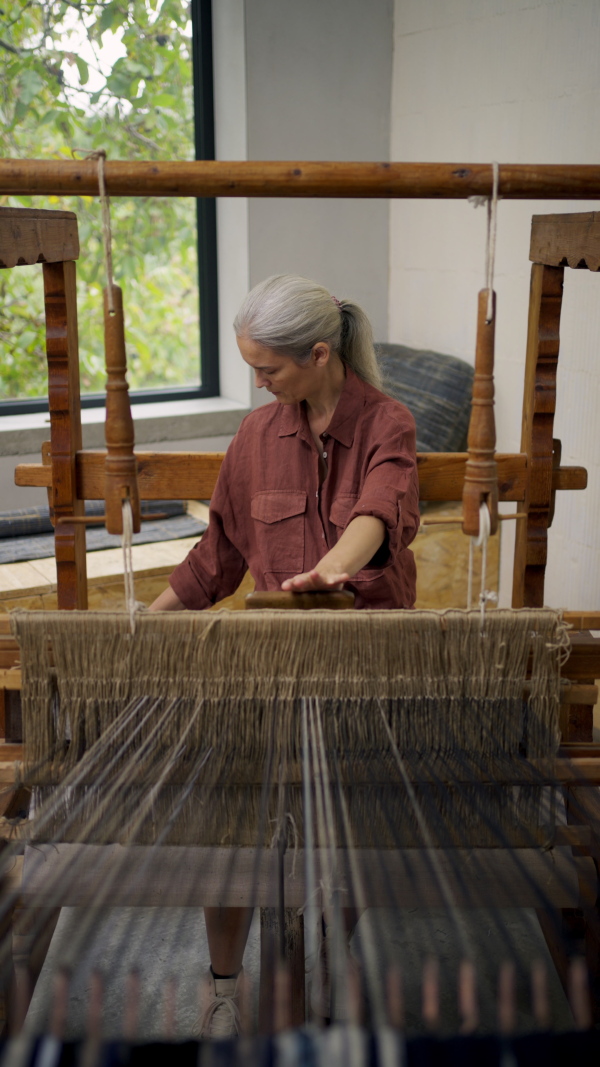 Woman in a weaving course is learning to weave on a loom. New Year's resolutions, developing personal creativity.