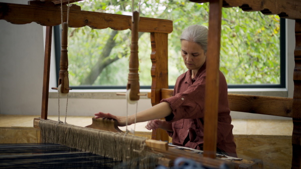 Woman in a weaving course is learning to weave on a loom. New Year's resolutions, developing personal creativity.