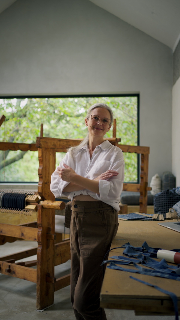 A happy businesswoman in weaving workshop. Sustainable business, using recycled materials in fashion.