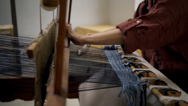 Close up of a woman in a weaving course is learning to weave on a loom. New Year's resolutions, developing personal creativity.