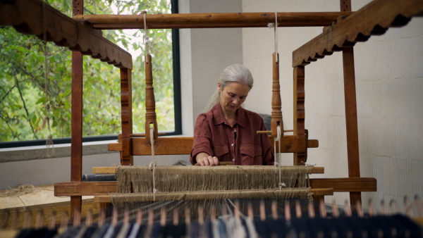 Woman in a weaving course is learning to weave on a loom. New Year's resolutions, developing personal creativity.