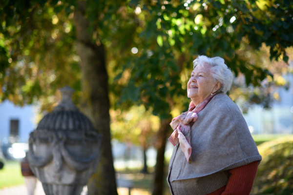 Portrait of elderly woman visiting a cemetery during warm autumn day