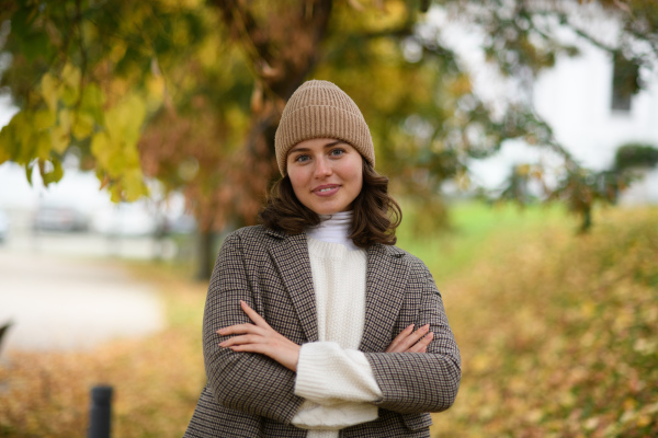 Portrait of a beautiful woman in the middle of autumn park. She smiles and looking at camera