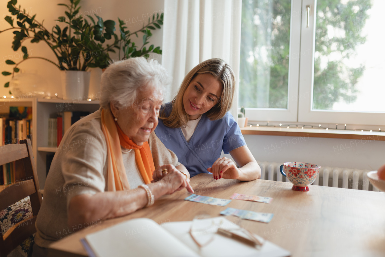 Social worker helping elderly lady with managing her finances and counting banknotes.