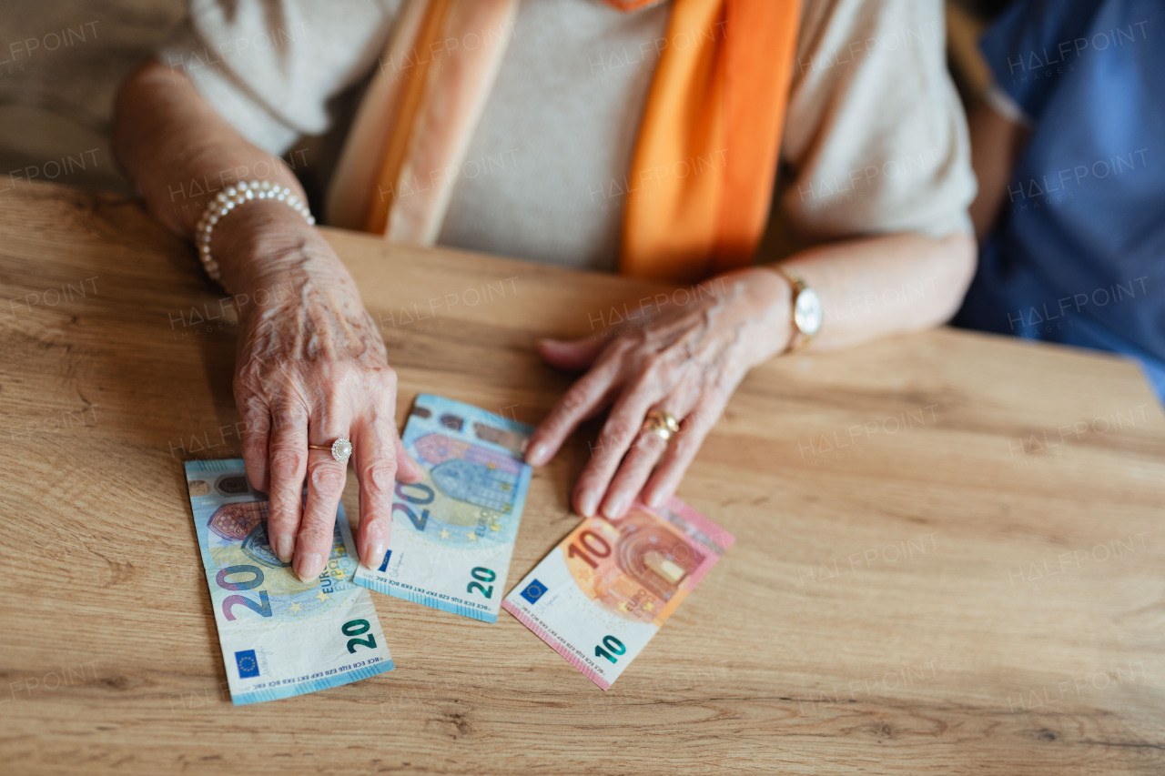 Close up of old woman laying banknotes on table. Concept of financial struggles for seniors.