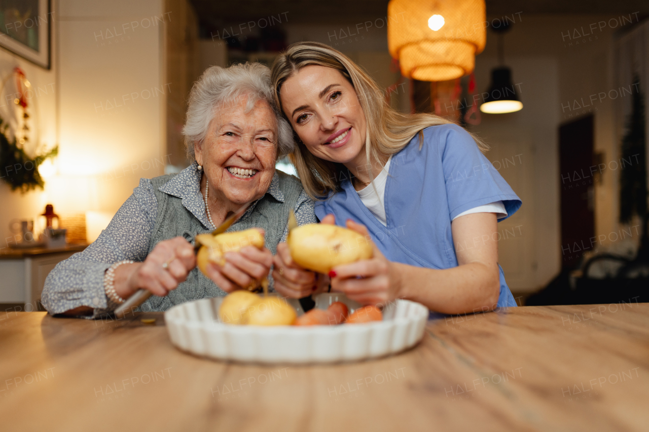 Portrait of an elderly companion assistant and senior woman peeling potatoes. Home health care services.