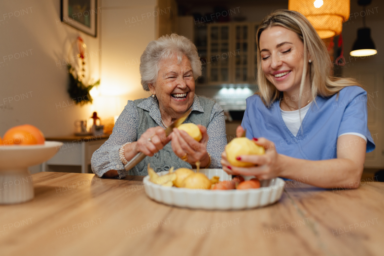 Portrait of an elderly companion assistant and senior woman peeling potatoes. Home health care services.