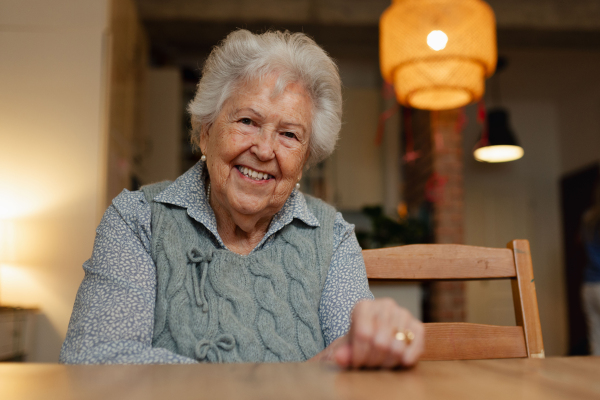 Portrait of lovely elderly woman at home, looking at camera and smiling.