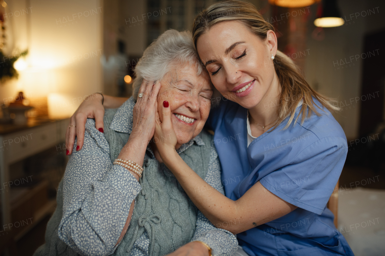 Caring healthcare worker visiting a senior patient at home, hugging her