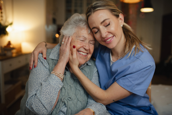 Caring healthcare worker visiting a senior patient at home, hugging her