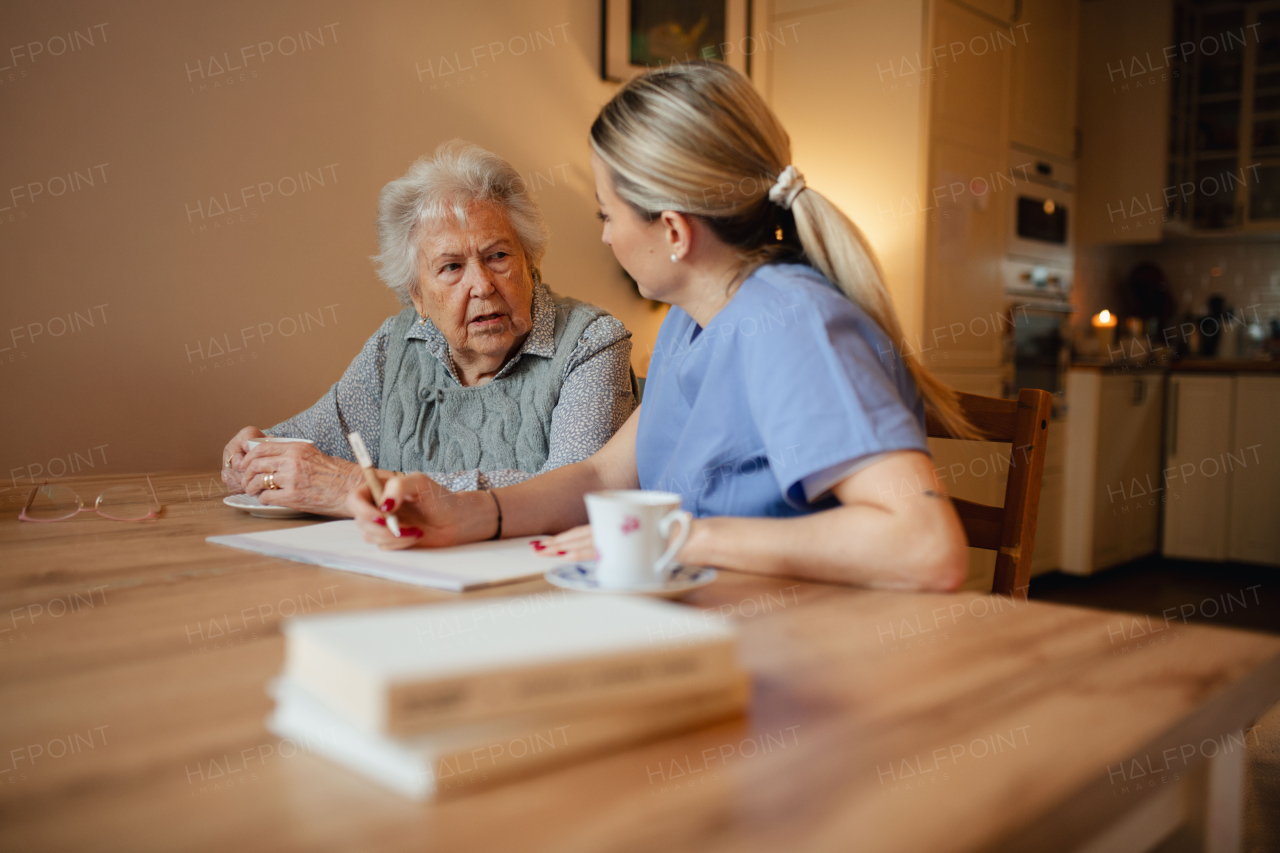 Social worker helping elderly lady with managing her finances and cworking on