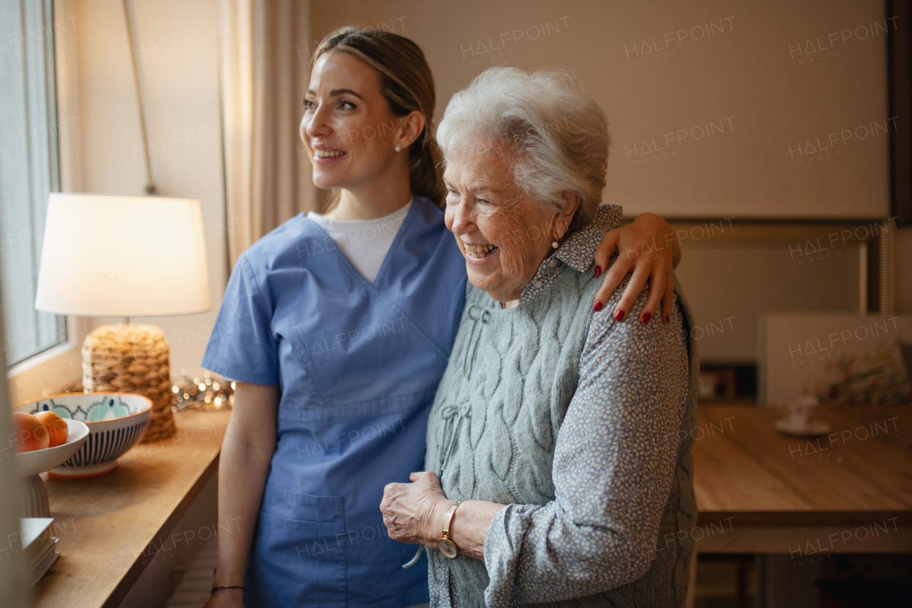 Caring healthcare worker visiting a senior patient at home, hugging her