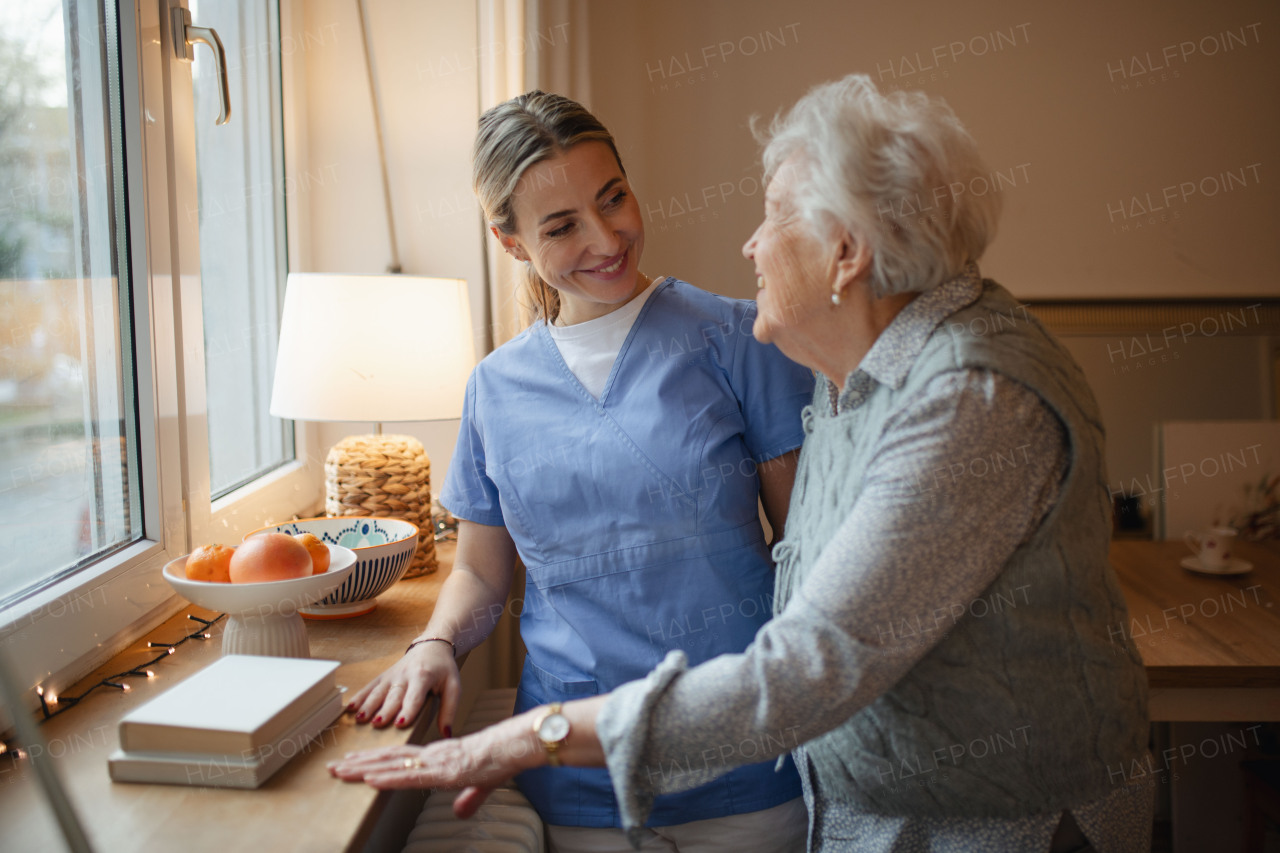 Caring healthcare worker visiting a senior patient at home, talking with her.