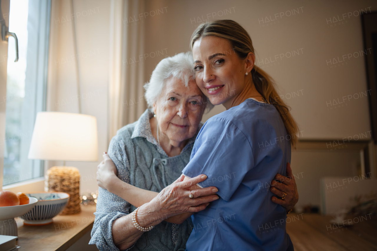 Caring healthcare worker visiting a senior patient at home, hugging her