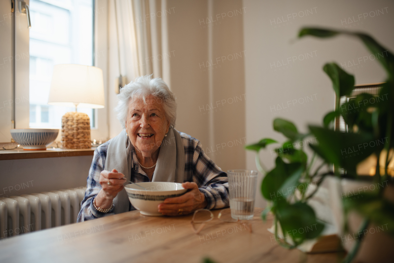 Poor and lonely elderly woman eating soup at the dining table.