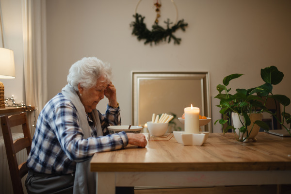 Side view of poor and lonely elderly woman eating soup at the dining table.