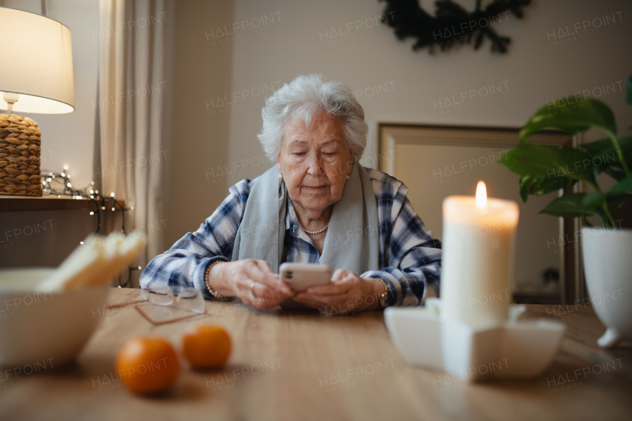 Elderly woman struggling to use a smartphone, looking confused.