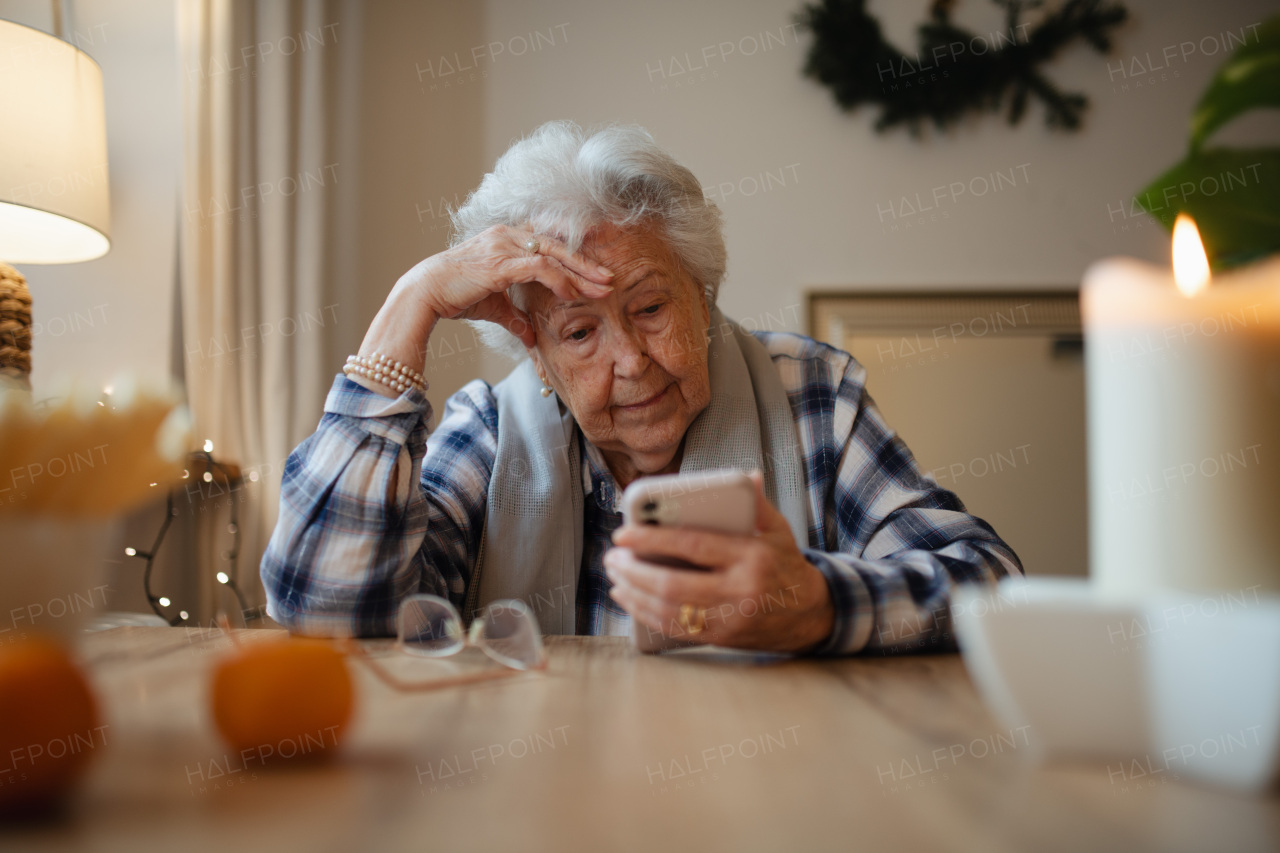 Elderly woman struggling to use a smartphone, looking confused.