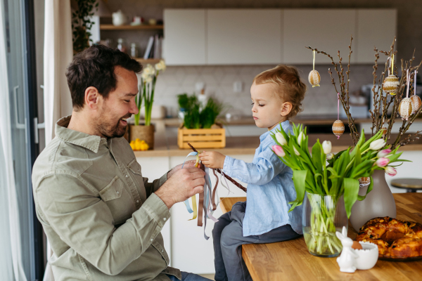 Father and little boy braiding easter whip from willow branches.